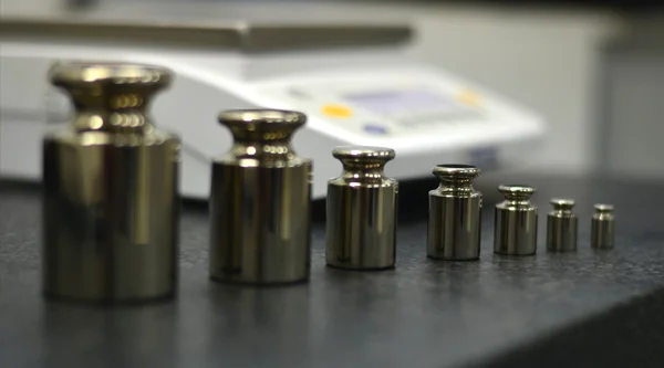 A set of calibration weights beside a precision balance