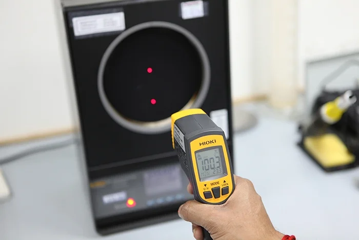 A handheld infrared thermometer being checked against a temperature source