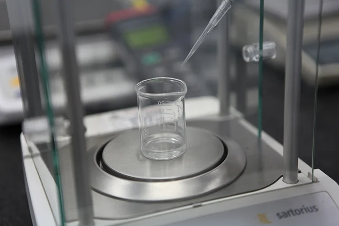 A pipette being checked against a precision analytical balance